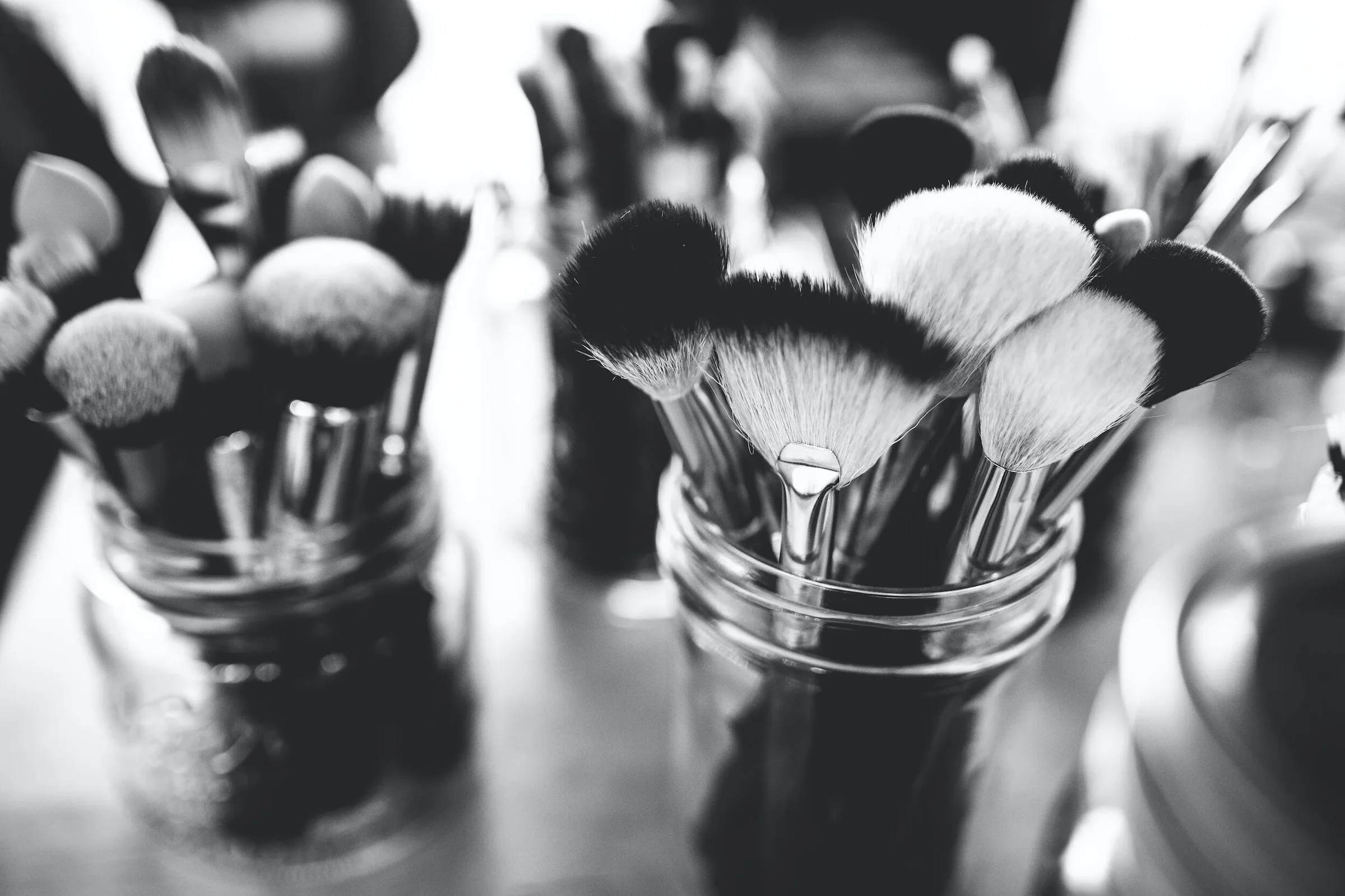 Close-up of makeup brushes in glass jars.