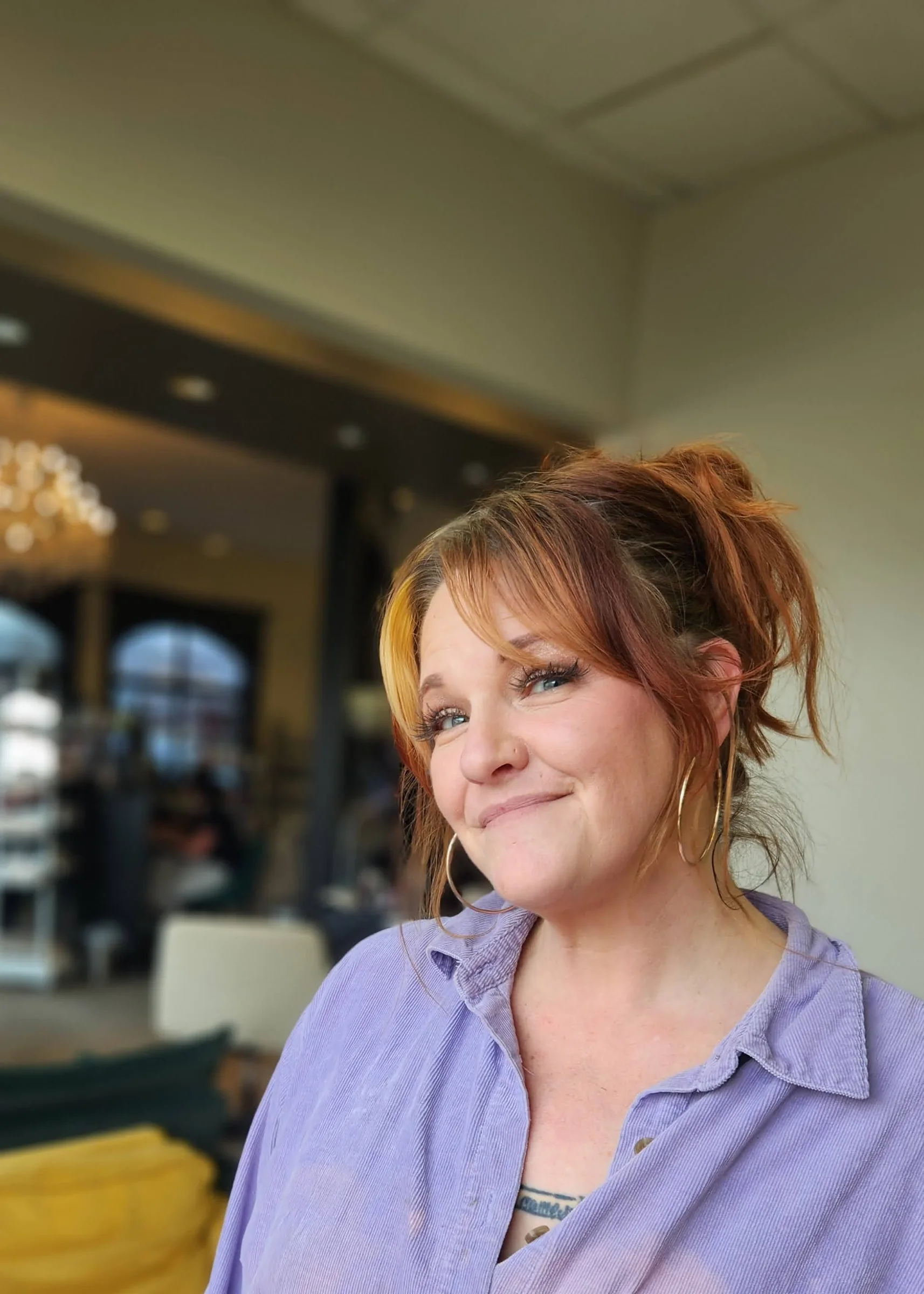 A woman with red hair, wearing large hoop earrings and a purple shirt