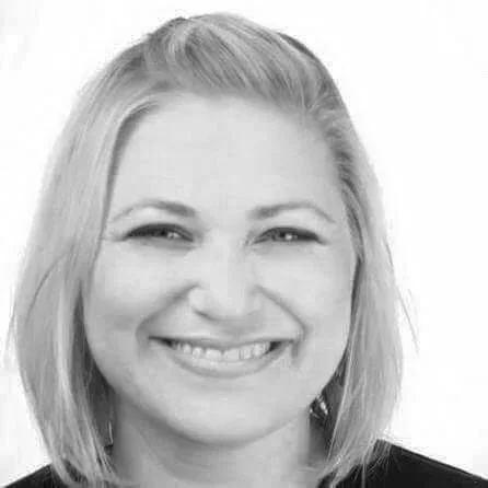 Black and white close-up of a smiling woman with straight, shoulder-length hair