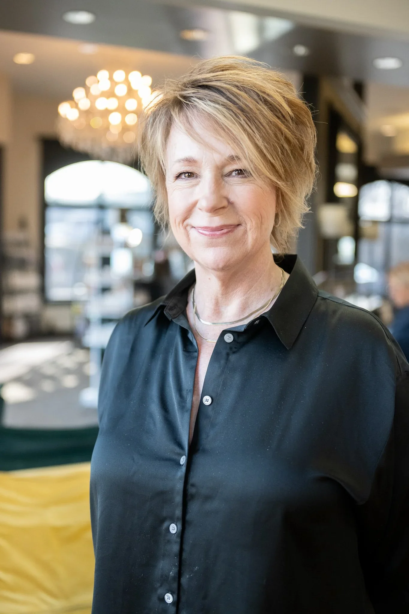 A woman with short, blonde hair wearing a black button-up shirt