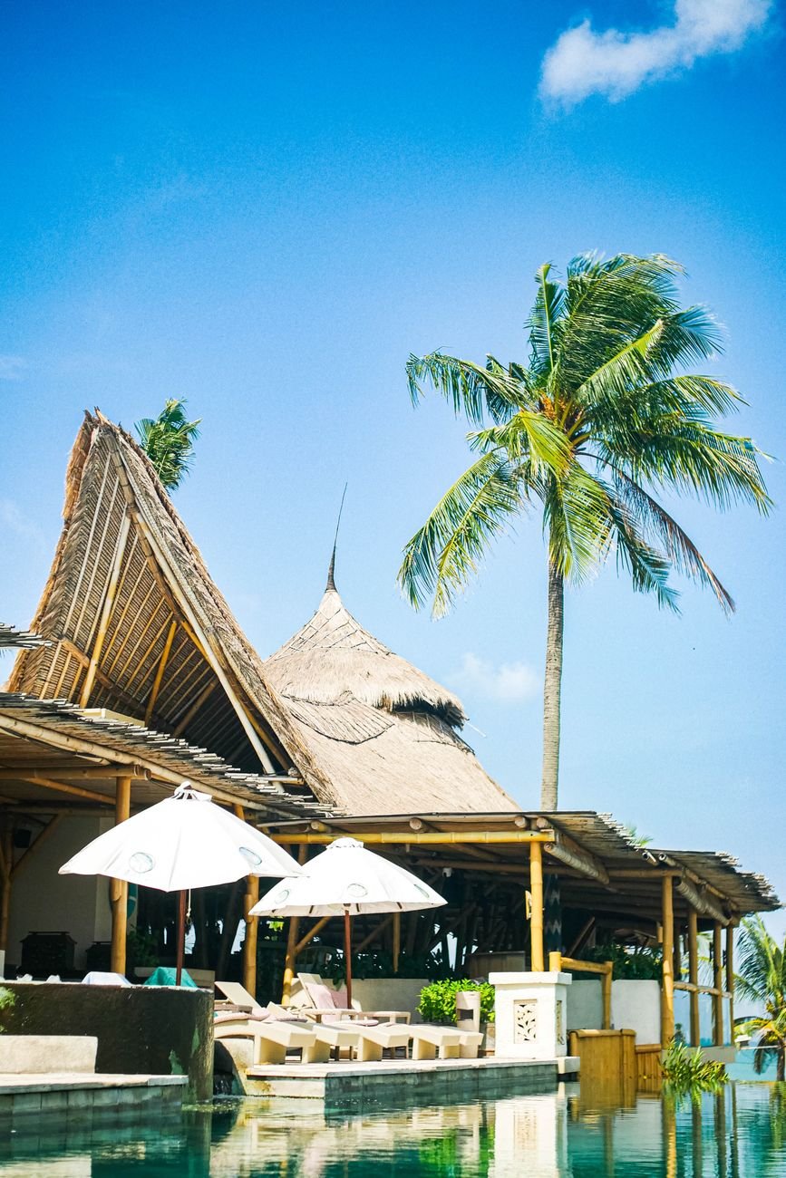 A serene tropical beach villa in Bali featuring lush palm trees and a tranquil poolside setting